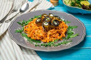 Pasta with eggplants, tomato, cheese and arugula photo