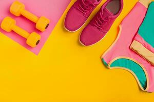 Athlete's set with female clothing, dumbbells and bottle of water on yellow background photo