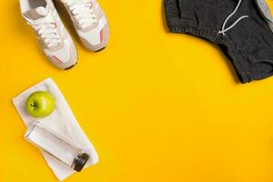 Athlete's set with female clothing and bottle of water on yellow background photo