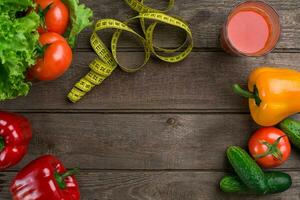 Glass of tomato juice with vegetables and measuring tape on table close-up photo