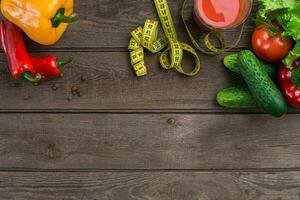 deporte y dieta. verduras, un vaso de tomate jugo y centímetro. pimientos, Tomates, ensalada en rústico antecedentes foto