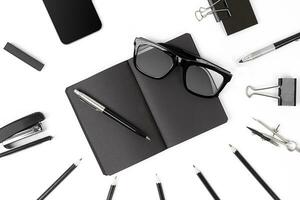 Blank notepad with clips, pens and glasses flat lay. photo