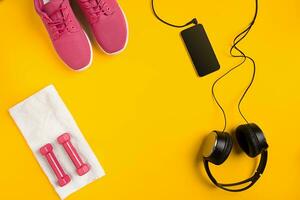 Athlete's set with female clothing, dumbbells and bottle of water on yellow background photo