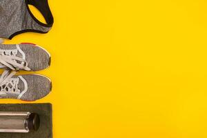 Athlete's set with female clothing, dumbbells and bottle of water on yellow background photo