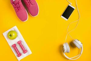 Athlete's set with female clothing, dumbbells and bottle of water on yellow background photo