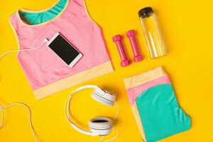 Sport equipment and clothes with mobile phone on yellow background. Top view photo