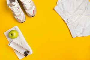 Athlete's set with female clothing and bottle of water on yellow background photo