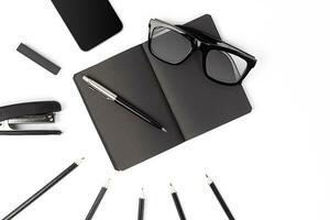 Blank notepad with clips, pens and glasses flat lay. photo