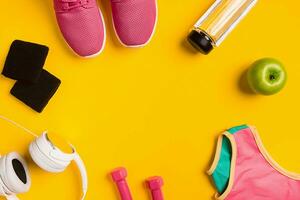 Athlete's set with female clothing, dumbbells and bottle of water on yellow background photo