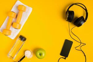 Athlete's set with female clothing, dumbbells and bottle of water on yellow background photo