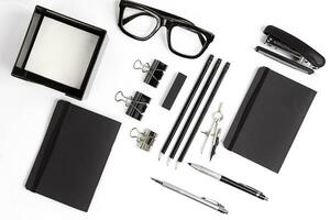 Blank notepad with clips, pens and glasses flat lay. photo