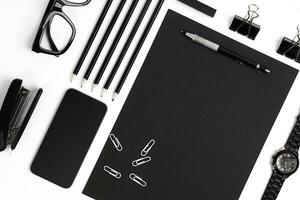 Blank notepad with clips, pens and glasses flat lay. photo