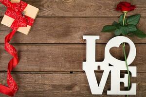 Box with red ribbon and rose on a wooden background, Valentine's Day concept photo