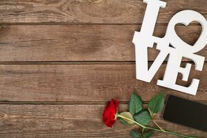 Red rose and smart over wooden background photo