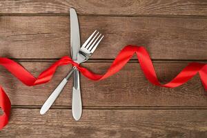 silver cutlery, fork and knife table setting on old rustic wooden background. photo