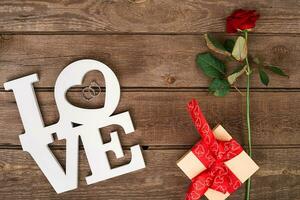 Box with red ribbon and rose on a wooden background, Valentine's Day concept photo