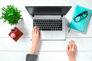 Laptop with blank screen and girl's hands. Flat lay, top view workspace photo