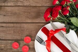 Valentines day table setting with plate, gift, red ribbon and roses. background photo