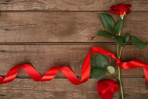 Present for St. Valentines Day - Red rose with ribbon on dark wooden background copyspace photo