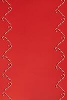 Christmas candies canes border on red background. Flat lay and top view photo