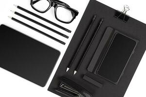 Blank notepad with clips, pens and glasses flat lay. photo