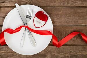 Valentines day table setting with plate, fork, knife, red heart, ring and ribbon. background photo