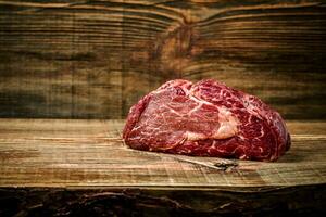 Dry aged Ribeye Steak with seasoning on wooden background. photo