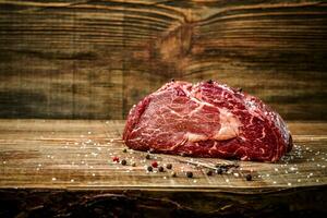 Dry aged Ribeye Steak with seasoning on wooden background. photo