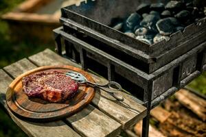 A thick strip steak being grilled outdoors photo