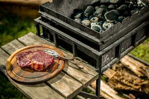 A thick strip steak being grilled outdoors photo