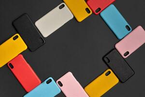 Set of colorful protective smartphone cases or covers on black studio background. Close up, copy space. Top view, flat lay, mock up photo