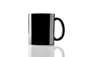 Black porcelain mug for coffee or tea on glossy surface isolated on white studio background. Mock up, template. Branding area. Close up, copy space photo