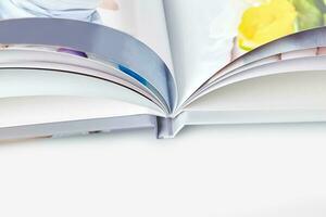 Open, high quality photo book with hardback and colorful pages on white studio background. Close up, copy space