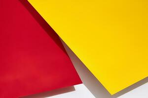 Red and yellow shadow-casting sheets of paper or stands above white surface. Advertising, branding area. Close up, copy space photo