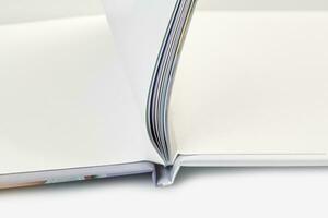 Open photo book with hardback and blank pages on white studio background. Close up, copy space