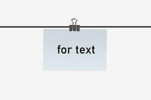 un pequeño pedazo de papel con inscripción para texto, sujetado por aglutinante acortar a un cable y colgando en él. aislado en blanco. cerca arriba, Copiar espacio foto
