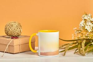 Colorful cup, cardboard box with skein of jute twine and bouquet of wild flowers on white tabletop against beige background. Close up, copy space photo