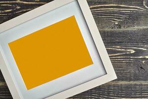 blanco y naranja moderno vacío foto marco en de madera antecedentes o escritorio. cerca arriba, Copiar espacio para tu texto o imágenes