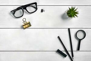 White wooden desktop with glasses, two pencils, stapler, magnifier, binder clip and succulent in a pot on it. Close up, copy space photo