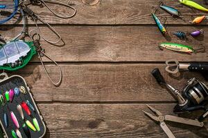 Fishing tackle - fishing spinning, fishing line, hooks and lures on wooden background. photo