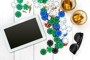 Gambling. Poker chips, cards and the dice nearby tablet on wooden table. Top view. Copyspace. Poker photo
