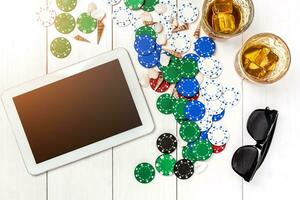 Gambling. Poker chips, cards and the dice nearby tablet on wooden table. Top view. Copyspace. Poker photo