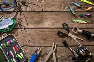 Fishing tackle - fishing spinning, fishing line, hooks and lures on wooden background. photo