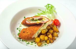 Cutting cordon bleu with cheese, turkey, crackers crumbs, potatoes. photo