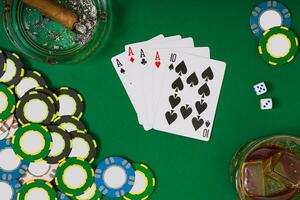 gambling, fortune and entertainment concept - close up of casino chips, whisky glass, playing cards and cigar on green table surface photo