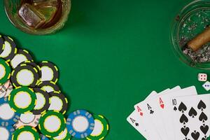 juego, fortuna y entretenimiento concepto - cerca arriba de casino papas fritas, whisky vaso, jugando tarjetas y cigarro en verde mesa superficie foto