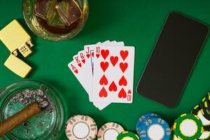 gambling, fortune and entertainment concept - close up of casino chips, whisky glass, playing cards and cigar on green table surface photo