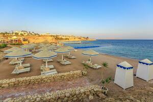 Beach with deck chairs and parasol during sunset photo