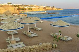 playa con cubierta sillas y sombrilla durante puesta de sol foto