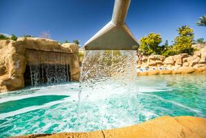 Stream water out of artificial waterfall in outdoor pool photo